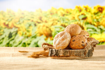 Fresh bread rolls on wooden table and countryside background.