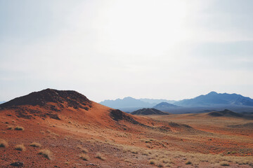 Fototapeta premium Vast Expanses: The Striking Contrast of Red Desert Hills and Distant Mountains