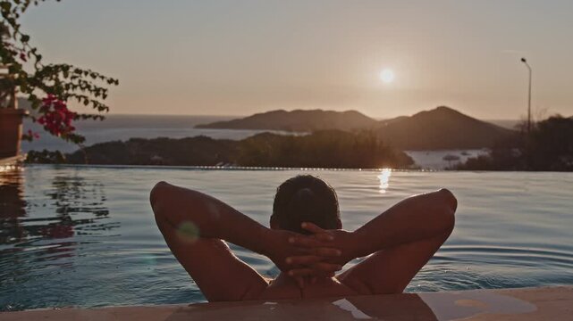A handsome mixed race man in a view pool, looking at the sunset