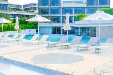 Empty swimming pool with sunbed and white umbrella in resort hotel for vacation leisure and white sand,resort neary sea and beach in summer..