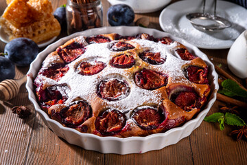 Autumn new york plum pie, tasty cinnamon spices plum torte cake on rustic cozy wooden background, copy space