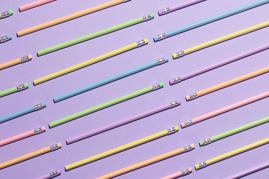 Colorful pencils arranged in a pattern on a purple background