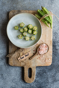 Sliced bamia on wooden board with raw food tag and spices