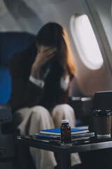 Photo of a frustrated woman sitting on an airplane with her head in her hands. Asian woman sitting in a seat in airplane