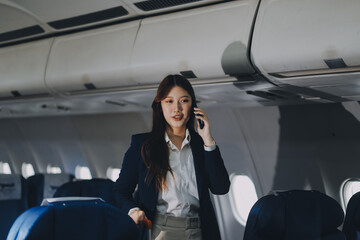 Businesswoman, confident tourist walks with suitcase, checks seat, flight number, puts her suitcase on shelf inside airplane travel lifestyle concept.