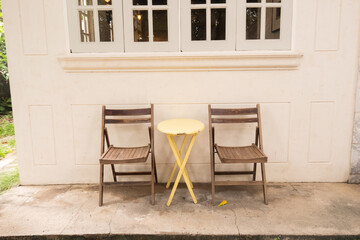 Yellow table and wooden chairs at cozy house or restaurant in garden,modern home decor,Contemporary interior design of dining space,minimal concept.