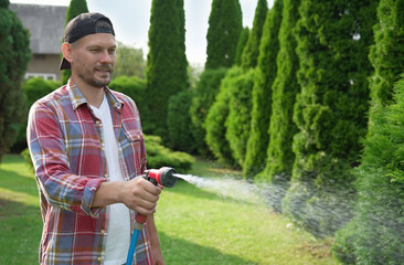 Man watering lawn with hose in backyard