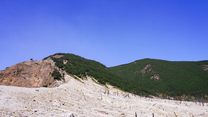 Barren mountain landscape with sparse vegetation under a clear blue sky. Ideal for nature and travel themes