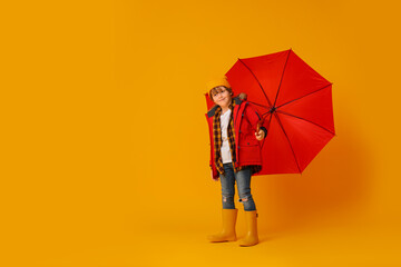 Little boy with red umbrella on orange background