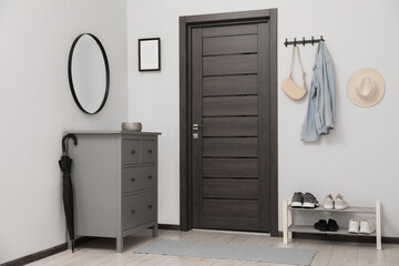 Chest of drawers, mirror and shoe storage bench in hallway. Interior design