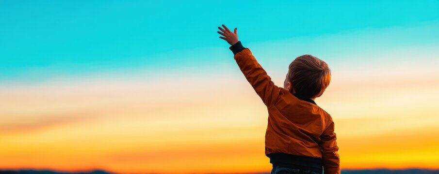 Silhouette of a child reaching towards the sky at sunset.