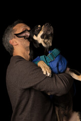 Obraz premium A man is hugging a dog wearing a blue jacket