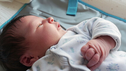 Newborn baby during first days of life, close-up face and hands moving and observing the world, initial week of life