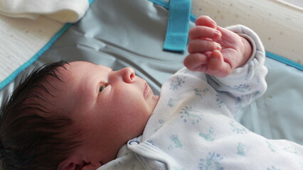 Newborn baby during first days of life, close-up face and hands moving and observing the world,...