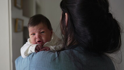 Mother holding newborn baby in arms during first week of life, nurturing maternal caring love of...