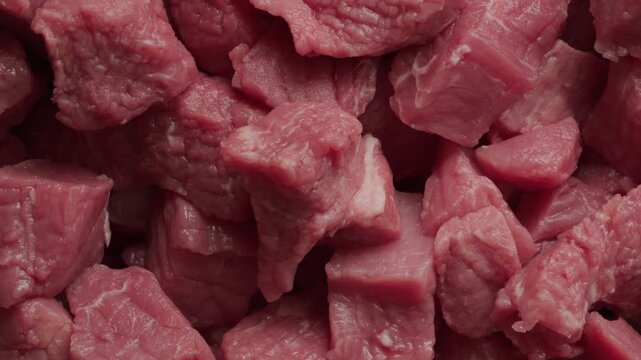 Raw lean beef in pile chopped into cubes background rotating macro