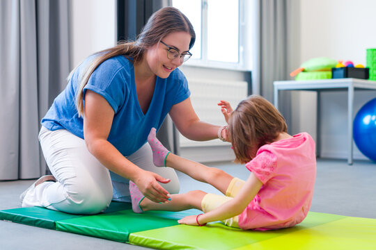 Child with physical disability in physical therapy session. Child living with cerebral palsy exercising with her therapist during physiotherapy.