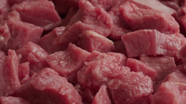 Raw lean beef in pile chopped into cubes background rotating macro