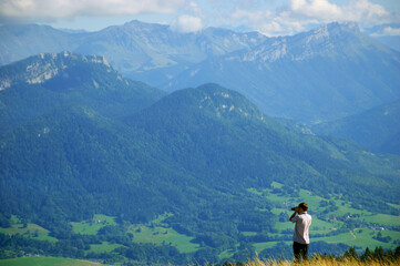 Young unrecognizable man taking picture of idyllic summer landscape with Mont Blanc in Alps mountains. Annecy lake area, Haute-Savoie, France. 