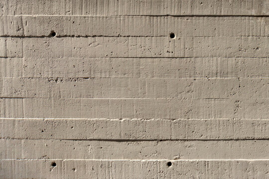 Concrete wall showing the wood imprint pattern of the planks it was formed from.