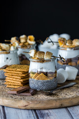 Smores chia puddings on a wooden board, surrounded by ingredients.