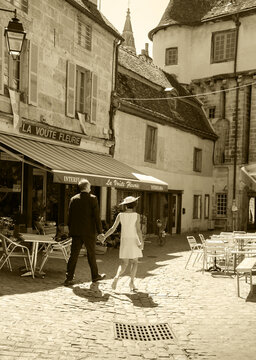Semur-en-Auxois, France - August 22, 2015: Unrecognizable mature couple walk in historic centre of medieval town of Semur-en-Auxois which is one of the most picturesque cities of Burgundy. Sepia photo