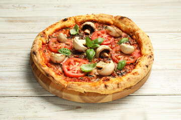 Tasty pizza with basil, mushrooms and tomato on wooden rustic table
