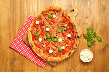Tasty pizza with basil, mushrooms, mozzarella and tomato on wooden table, flat lay