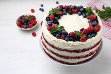 Tasty sponge cake with different berries and mint on white wooden table