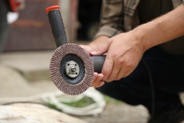 Man with angle grinder outdoors, closeup view