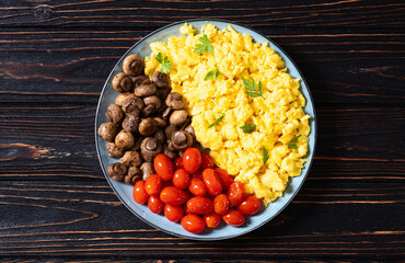 Homemade scrambled eggs with mushrooms and cherry tomatoes