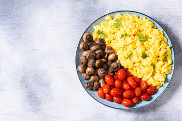 Homemade scrambled eggs with mushrooms and cherry tomatoes