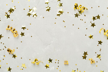 Golden gift boxes and confetti on concrete background, top view