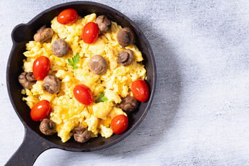 Healthy vegetarian breakfast . Scrambled eggs in pan with cherry tomatoes and parsley