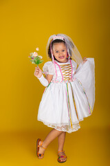 Cheerful child dressed as a bride holding a bouquet of flowers and posing for the camera.