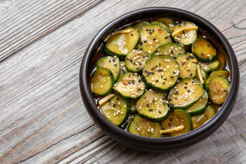 Sunomono, Japanese Cucumber Salad, sliced cucumbers pickled in soy sauce, rice vinegar, and sugar in a bowl on a rustic wooden table with space for text.