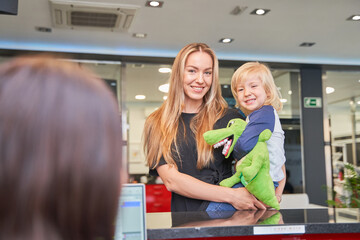 mother holds her child in her arms at the dentist's reception desk