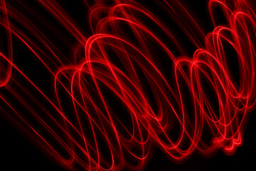 Light Painting Photography - swirly waves of neon red light against a black background. Long exposure photograph. 