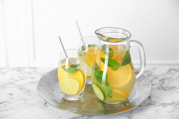 Freshly made lemonade with mint in jug and glasses on white marble table