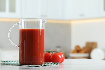 Tasty tomato juice in jug and vegetables on white marble table. Space for text