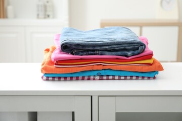 Stack of clean clothes on white dresser indoors