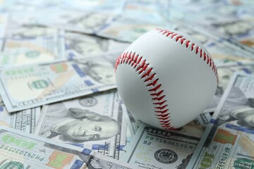 Baseball ball on many dollars bills, closeup
