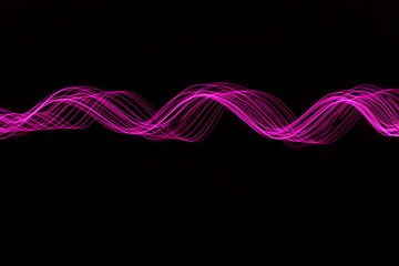 Long exposure photograph - Light Painting Photography - swirly waves of neon pink purple light against a black background