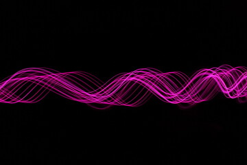 Long exposure photograph - Light Painting Photography - swirly waves of neon pink purple light against a black background