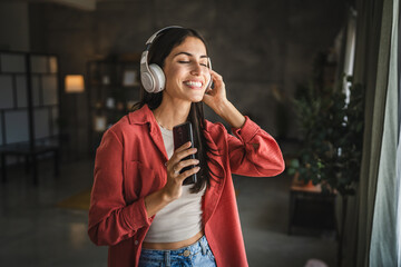 Adult woman with headphones listen to music and sing on mobile phone
