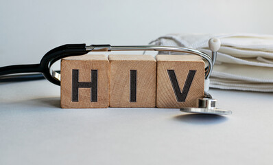 HIV inscription on wooden cubes isolated on white background, medicine concept. A stethoscope and protective masks are on the table next to it.