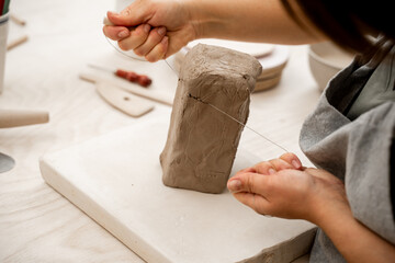 Cutting off the necessary piece of clay before forming a pottery product. Learning how to cut clay...