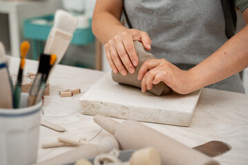 Wedging the clay before starting making a pottery project to create proper consistency. Removing air bubbles from clay before modeling to avoid the ruination of a ceramic product.