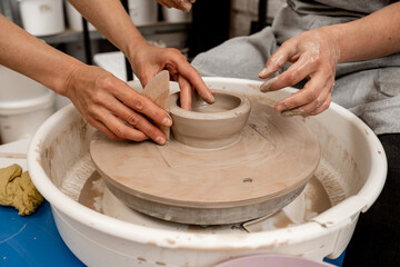 Making smooth edges of pottery with a wooden scraper and a pottery wheel. Cutting the lines on sides of a clay product with a wooden scraper.