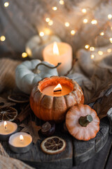 Atmospheric candle - shape of pumpkins, autumn decor on grey fall rainy day. Autumn cozy home atmosphere and inspiration, hygge concept. Aromatherapy, warming, relaxation. Wooden background